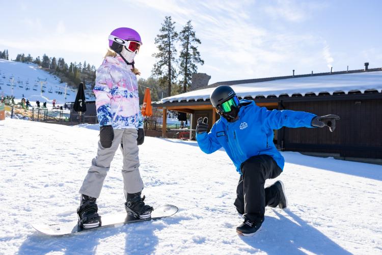 在加利福尼亚州大熊湖的雪峰滑雪胜地,一名教练指导一名学生滑雪板。