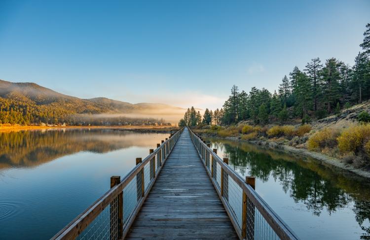 A photo from one of the Boardwalks in Big Bear Lake California, the sunrise visible through the clouds in the distance.