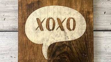 白色背景上有一个绘有 XOXO 字样的木质标志。
